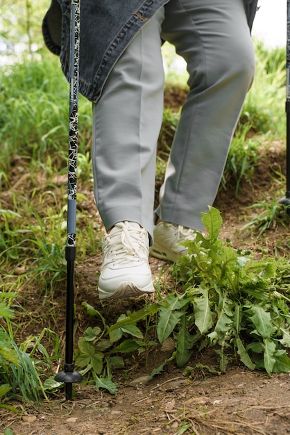 Senior Woman Trekking Dans La Nature. Une Femme âgée Descend La Colline à L'aide De Bâtons De Marche. Gros Plan Sur Des Bottes, En Descendant. Randonnée, Concept De Mode De Vie Actif