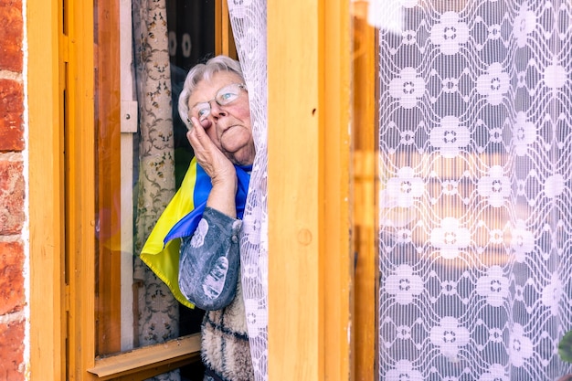 Senior woman with ukraine le drapeau pleurant la souffrance et priant la paix pendant la guerre conflit entre ru