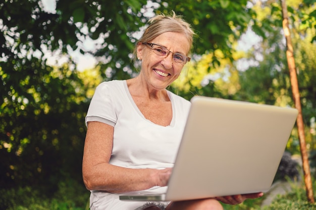 Senior woman working en ligne avec ordinateur portable