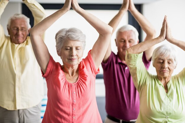 Seniors faisant du yoga avec les yeux fermés