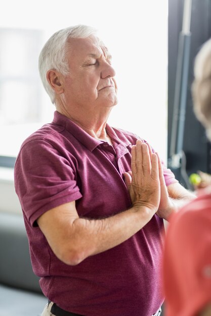 Seniors faisant du yoga avec les yeux fermés