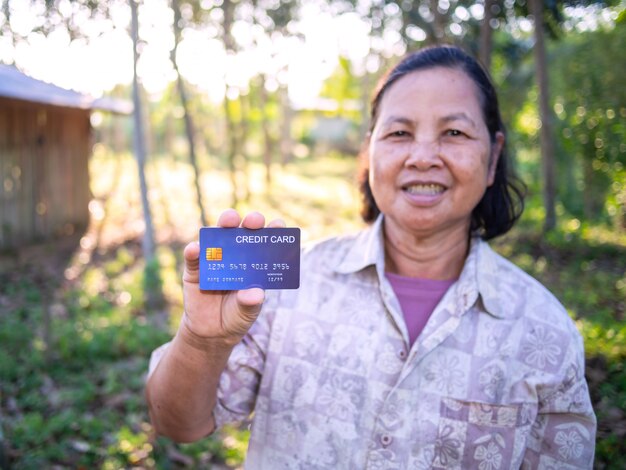 Senoir Asiatique Souriant Femme Montrant La Carte De Crédit.