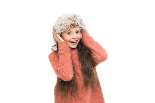 Sensation de chaleur. Entretien des vêtements de fourrure. Le chapeau doux aux cheveux longs pour enfants apprécie la douceur. Concept de mode d'hiver. Bonnet chaud pour temps froid. Kid girl wear hat avec oreillettes fond blanc. Accessoire en fourrure douce.