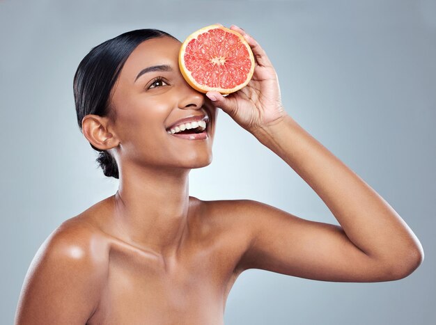 Sensation fruitée. Photo recadrée d'une jolie jeune femme posant en studio sur fond gris.