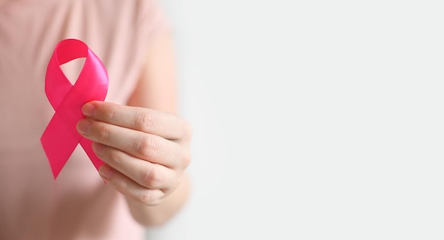 Sensibilisation au cancer du sein et journée rose d'octobre Femme en T-shirt rose avec une main tenant un ruban rose