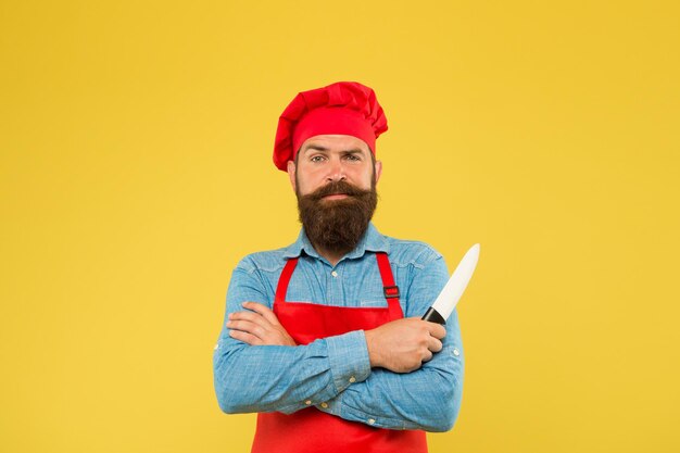 Sentez-vous bien manger le meilleur menu offre confiant chef barbu heureux uniforme rouge Chef masculin coupé avec un couteau hipster mature avec un visage sérieux chef barbu mains croisées boucher brutal en tablier