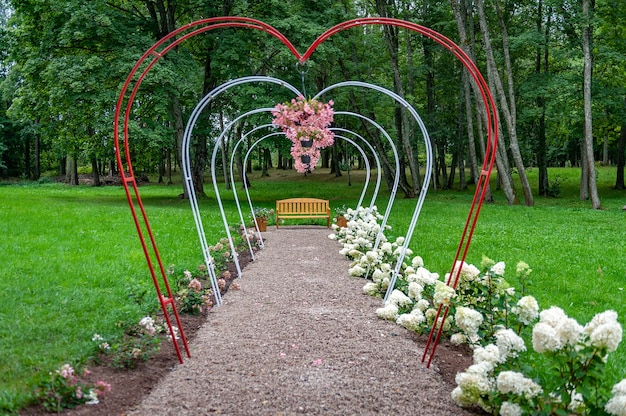 Sentier des arches cardiaques dans le parc. Arcs de fleurs en forme de coeur de jardin d'été.