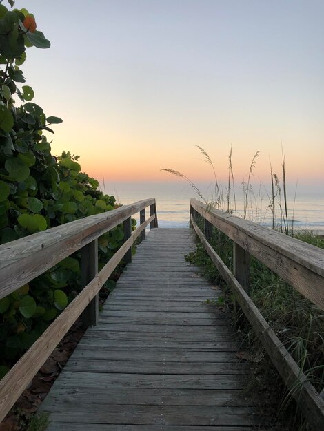 Photo un sentier en bois menant à la mer contre le ciel au coucher du soleil