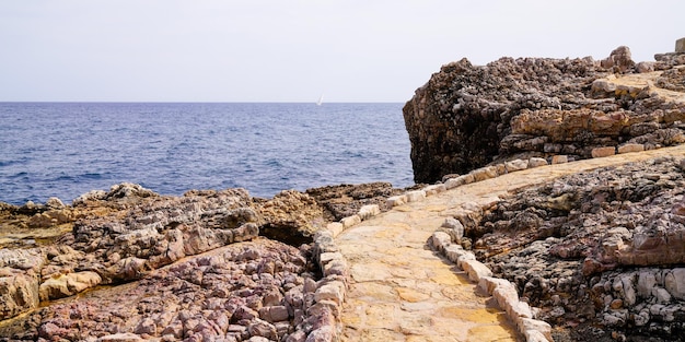 Sentier des pierres méditerranéennes dans les rochers accès à la mer de la plage sur la côte JuanlesPins à Antibes France dans l'en-tête web panoramique