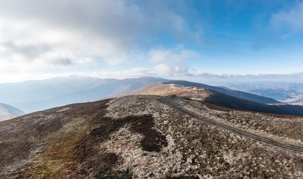 Sentiers étroits parmi les prairies sur la crête de la haute montagne sous des nuages blancs moelleux flottant sur le ciel bleu par une vue panoramique ensoleillée