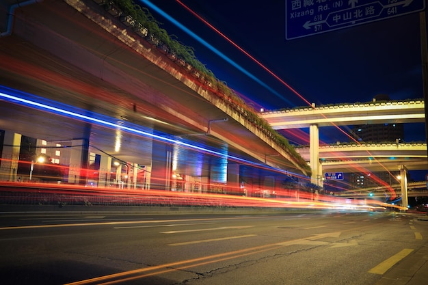 Sentiers de lumière sur la route de la ville avec viaduc d'autoroute