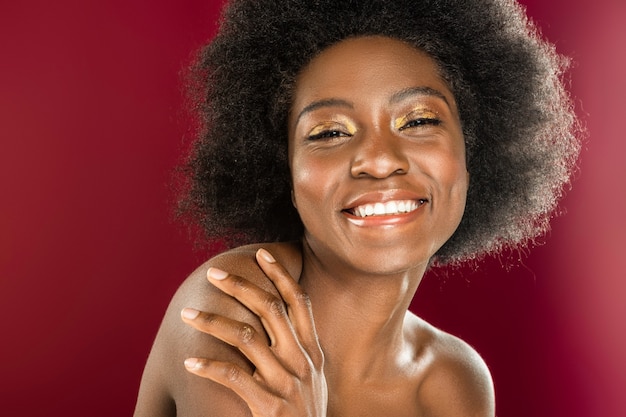 Sentiment de bonheur. Joyeuse femme afro-américaine qui vous sourit tout en se sentant heureuse