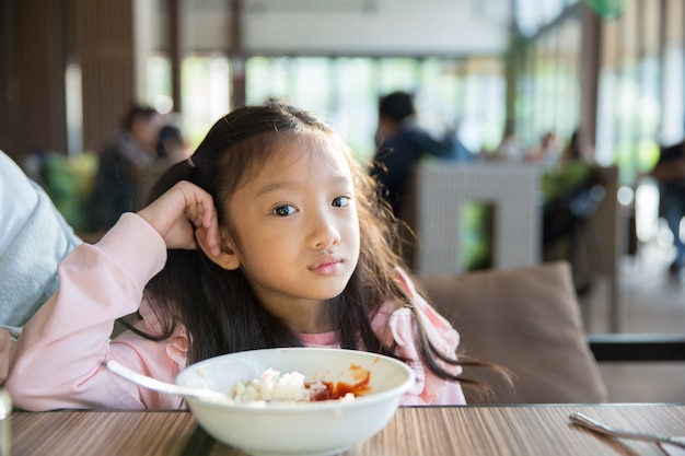 Le sentiment de la petite fille asiatique portait la nourriture avec le riz et la sauce tomate