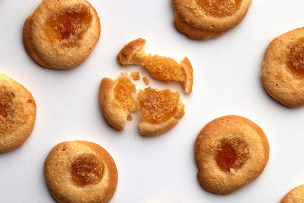 Sept biscuits faits à la main avec de la confiture d'abricots disposés en rangées égales sous un angle. isolé sur fond blanc