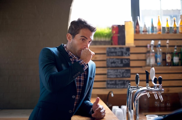 Les séquelles d'une journée d'indulgence Photo d'un beau jeune homme au bar couvrant sa bouche