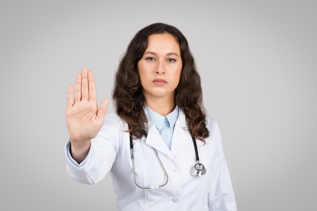 Serie jeune femme européenne médecin thérapeute en manteau blanc faisant stop signe avec la main et en regardant