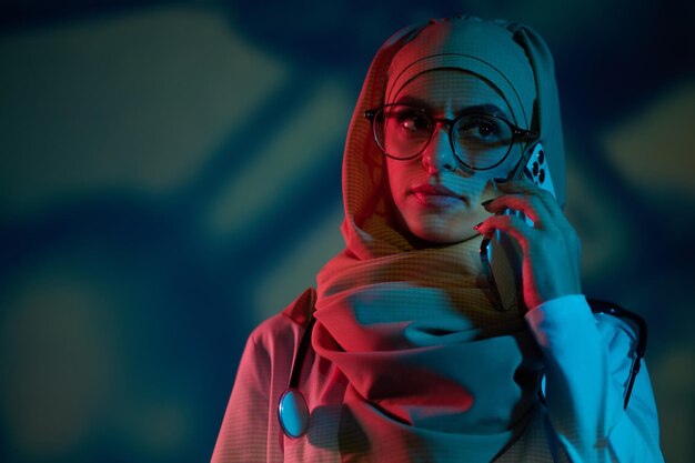 Photo sérieuse jeune femme médecin en hijab avec un téléphone à la main