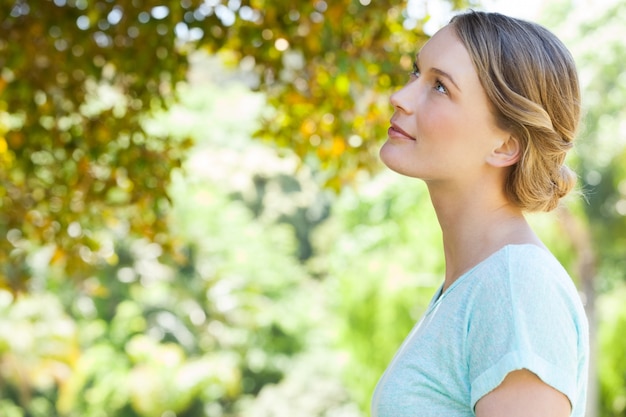 Sérieuse jeune femme regardant les feuilles dans le parc