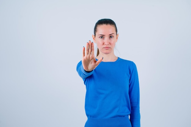 Sérieusement jeune fille montre un geste d'arrêt sur fond blanc