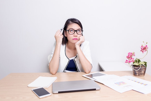 Sérieux exécutif asiatique femme trouver des idées tout en travaillant à son bureau avec ordinateur portable