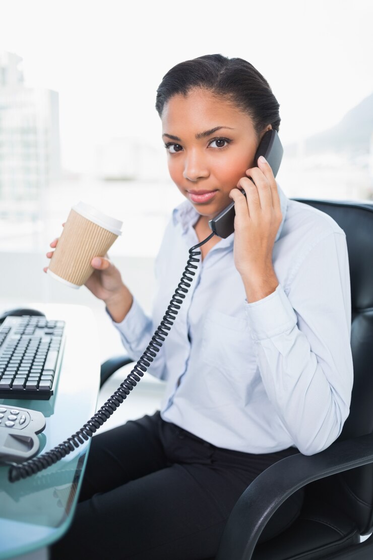 Photo sérieux jeune femme aux cheveux sombre tenant une tasse de café tout en répondant au téléphone