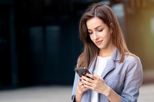 Sérieux jeune homme d'affaires dans des verres, femme d'affaires regarde son téléphone portable