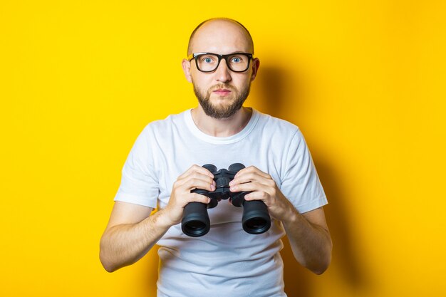 Sérieux jeune homme avec une barbe tient des jumelles