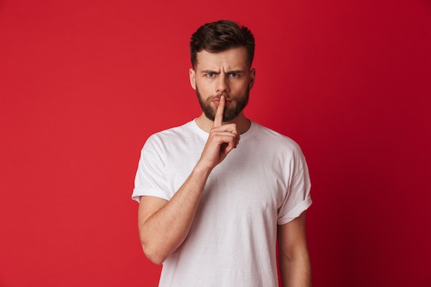 Sérieux jeune homme montrant le geste de silence