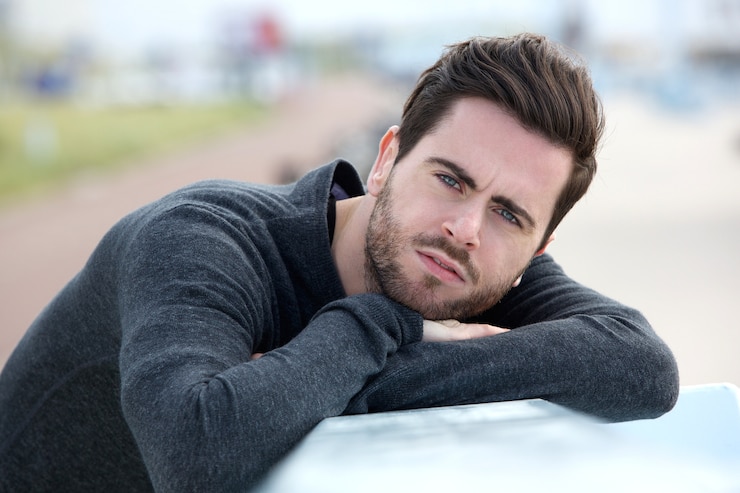 Photo sérieux jeune homme posant à l'extérieur