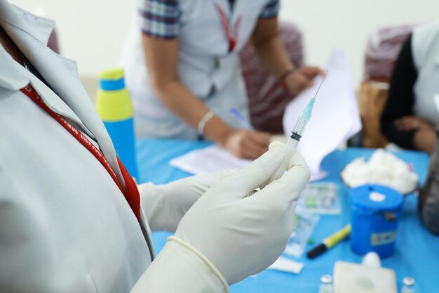 Seringue avec aiguille contenant un vaccin injecté dans une main gantée