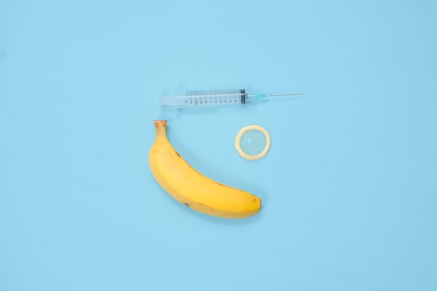 Seringue, banane et contraception isolés sur fond bleu