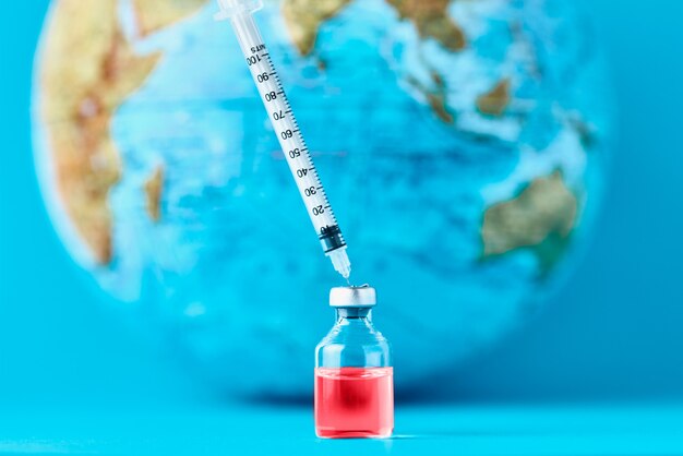 Seringue médicale et ampoule avec médicament contre le globe terrestre. Un concept d'épidémie, de virus et d'infection humaine