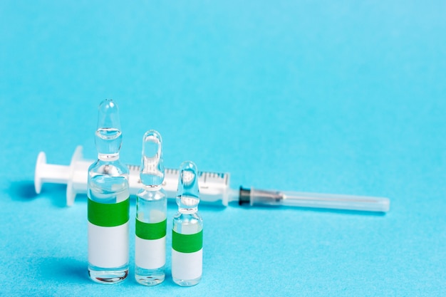 Une seringue médicale et trois ampoules de différentes tailles contenant un vaccin ou d'autres produits pharmaceutiques.