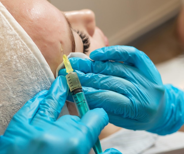 Seringue avec plasma sanguin d'un patient dans la main d'un cosmétologue pour un plasmolifting d'un visage de femme