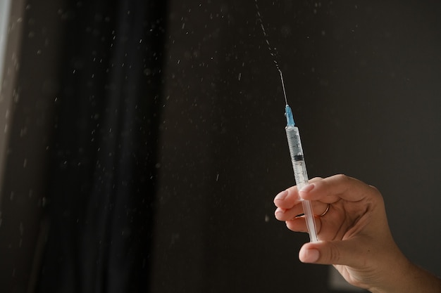 seringue avec vaccin à disposition sur fond sombre