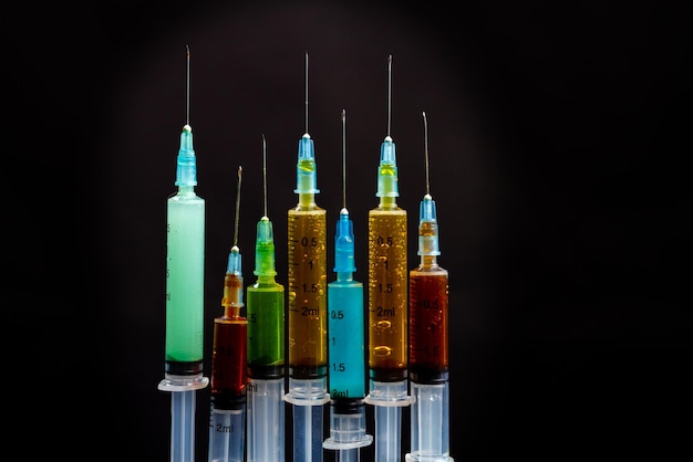 Seringues verticales avec des liquides de drogue colorés sur fond gris concept de vaccination ou de toxicomanie