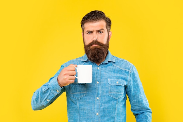 Serious caucasian man holding tea mug fond jaune