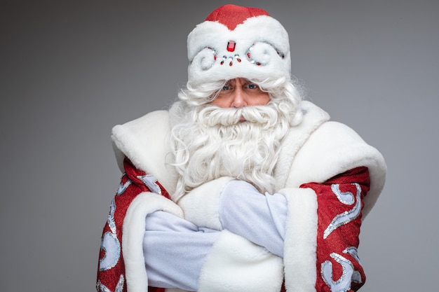 Serious Santa Claus croisa les bras sur sa poitrine et insatisfait, portrait en studio sur fond gris