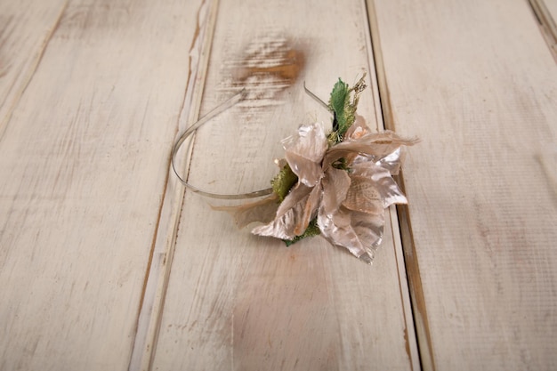 Un serre-tête à fleurs argentées avec une feuille verte et un nœud en ruban argenté.