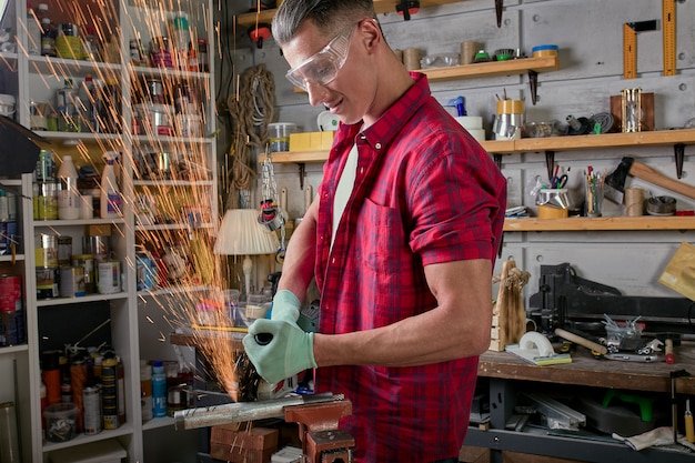 Serrurier coupe du métal avec une rectifieuse, scie mécanique mécanicien coupe.