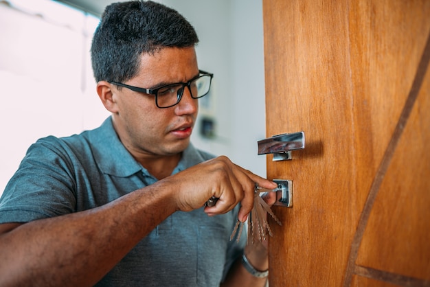 Serrurier ouvrant une porte Les mains masculines réparent ou installent une serrure de porte en métal avec un tournevis