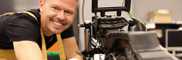 Un serrurier souriant réparant une moto avec une clé dans le centre de service entretien du moteur