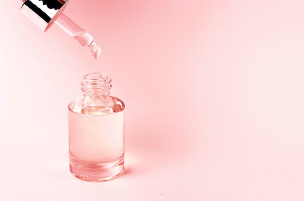 Sérum et compte-gouttes sur un fond rose, concept de cosmétiques naturels