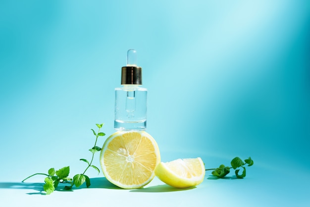 Sérum visage aux agrumes citron et vitamine C dans un flacon en verre avec une pipette sur fond bleu