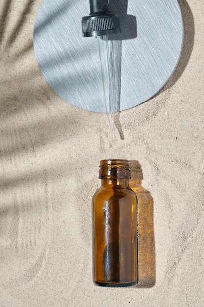 Sérum visage de bouteille en verre avec une pipette sur fond naturel avec de l'huile essentielle de sable