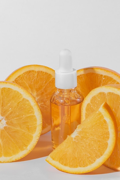 Photo serum de vitamine c à base d'huile essentielle d'agrumes avec des oranges juteuses fraîches sur fond blanc cosmétique de spa biologique avec ingrédients à base de plantes tonifiant dose élevée de vitamine c synthétique pour la peau