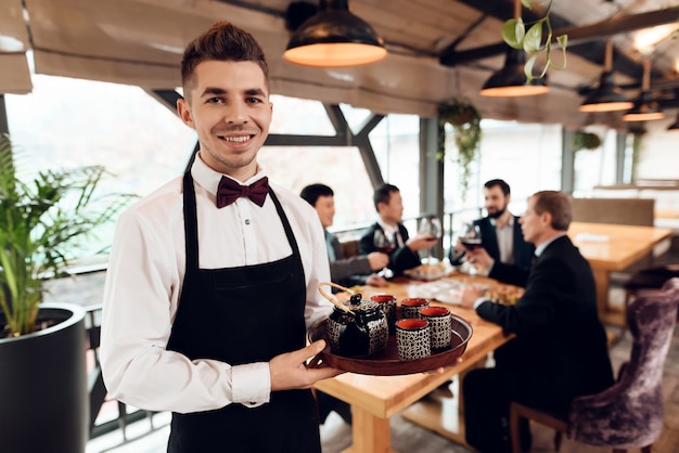 Photo serveur faisant le thé pour les hommes d'affaires asiatiques