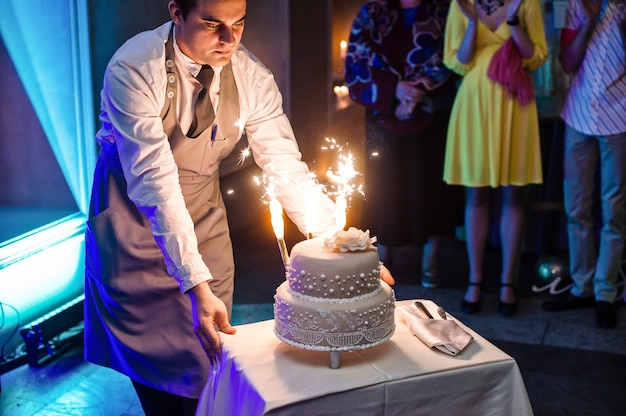 Le serveur fait un gâteau de mariage avec des bougies romaines