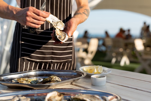 Le serveur ouvre des huîtres sur la terrasse d'été au bord de la mer