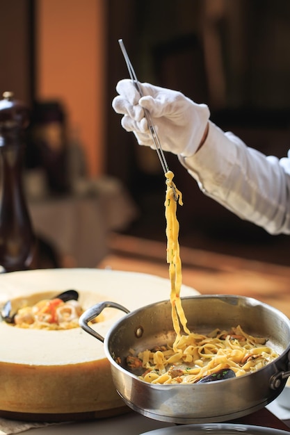 Le serveur prépare des pâtes aux fruits de mer et au parmesan